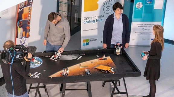 Ein Tisch von oben, auf dem die Erde und der Mars abgebildet ist. Die Roboter sollen darauf verschiedene Stationen anfahren.