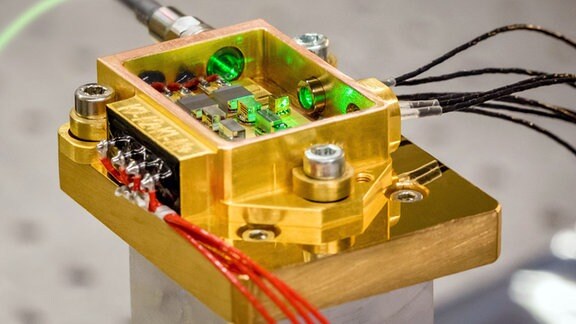 Das in Jena aufgebaute Festkörperlasermodul ist ein elektronisches Bauteil in goldener Farbe mit einer Lasereinheit in der Mitte.