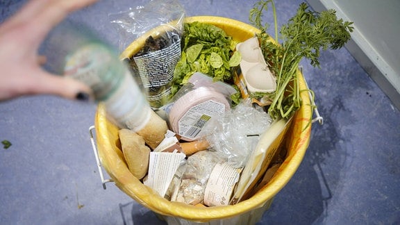 Lebensmittel mit abgelaufenem Haltbarkeitsdatum liegen in einem Mülleimer.