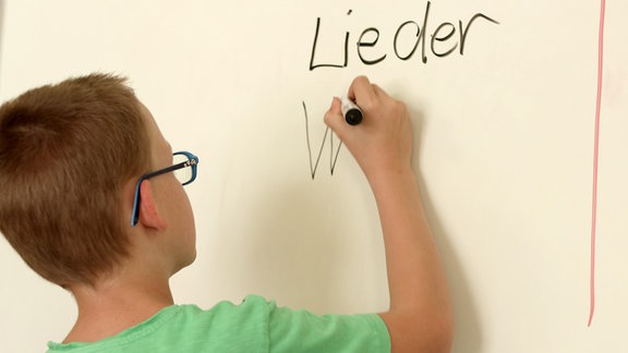 Ein Junge schreibt auf ein Whiteboard