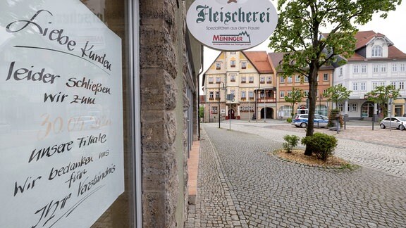 Ein handgeschriebenes Schild in einem Schaufenster am Marktplatz in Schleusingen weist auf die Schließung einer Filiale einer Fleischerei und Bäckerei hin.