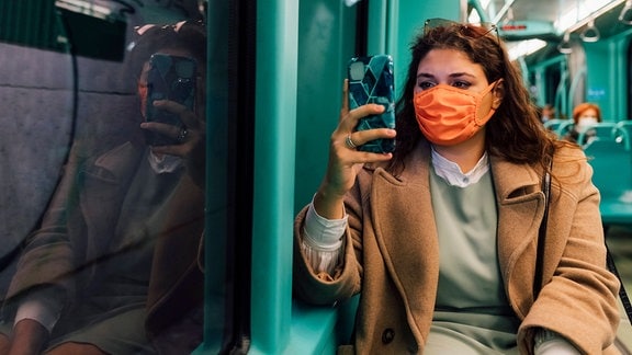 Junge Frau mit Maske in einer Bahn
