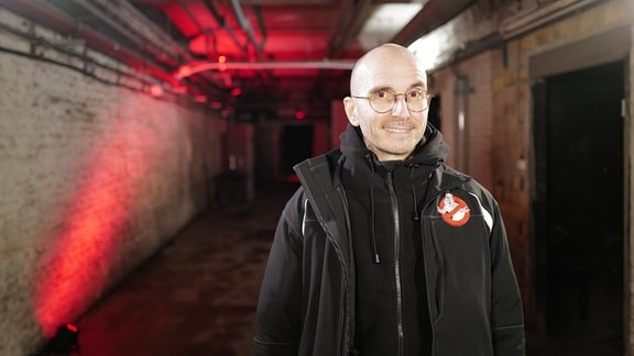 Ein lächelnder Mann mit Brille in einem Kellergang