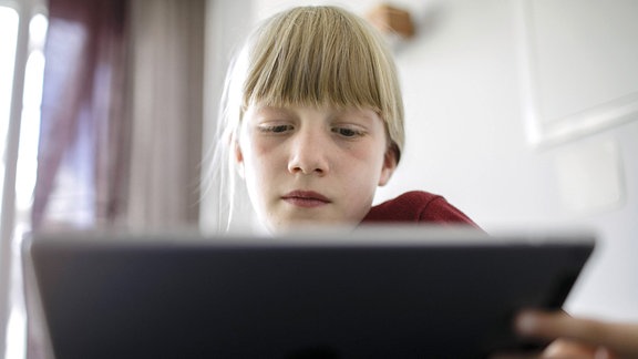 Ein Mädchen lernt oder spielt an einem Tablet.