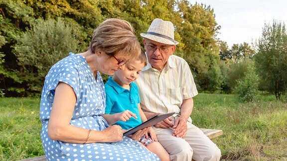 Kind erklärt Großeltern die Handhabung eines Tablet-PCs