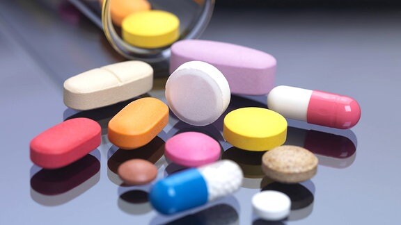 Verschiedene Tabletten und Kapseln neben einem Reagenzglas