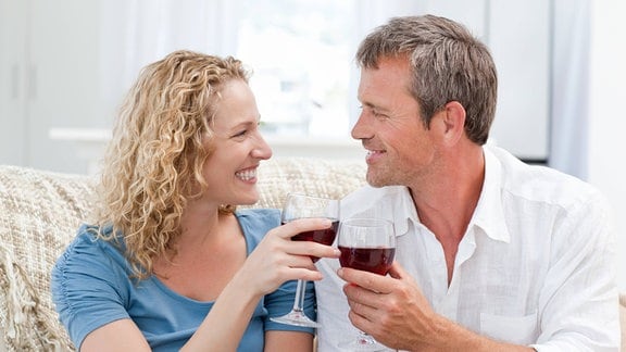 Paar stößt lächelnd mit Rotwein an