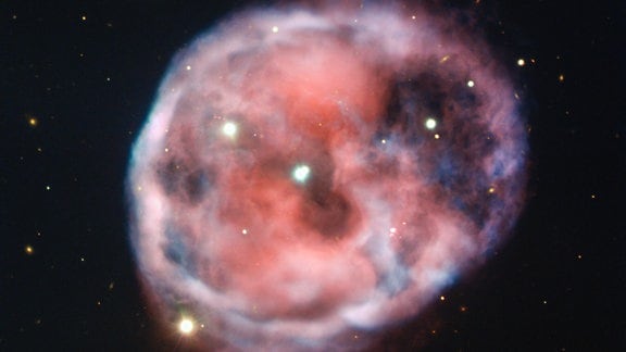Der unheimliche Totenkopfnebel, der mit dem Very Large Telescope (VLT) der ESO in verblüffender Detailgenauigkeit aufgenommen wurde, wird auf diesem neuen Bild in wunderschönen Rosa- und Rottönen dargestellt. Dieser planetarische Nebel, auch bekannt als NGC 246, ist der erste, von dem bekannt ist, dass er mit einem Paar eng verbundener Sterne assoziiert ist, die von einem dritten äußeren Stern umkreist werden