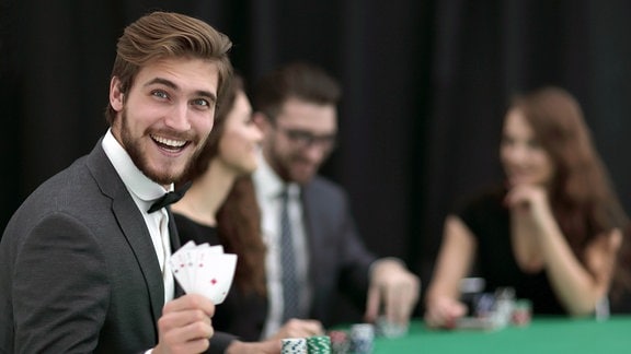 Spieler mit Karten in der Hand schaut lachend zur Kamera.