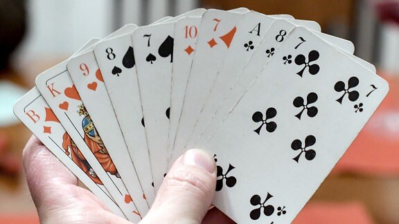 Ein Skatspieler hält Spielkarten in der Hand.