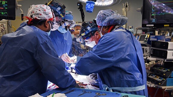 Ein Operationstisch mit mehreren Chirurgen während der Transplantation eines genetisch modifizierten Schweineherzens für einen menschlichen Patienten. Im Vordergrund liegt das OP-Besteck.