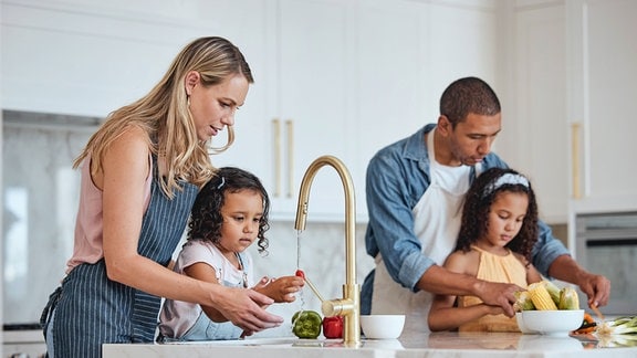 Kinder waschen mit ihren Eltern zusammen Gemüse