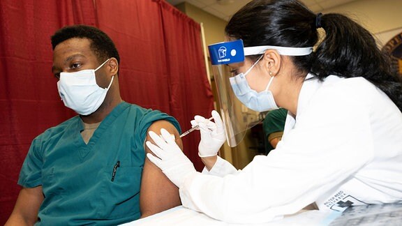 Der amerikanische Militärarzt Isaiah Horton bekommt als einer der Ersten das Pfizer COVID-19 Vaccinations geimpft.