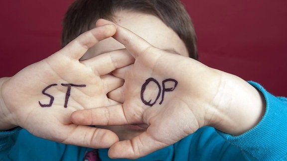 STOP steht auf den Handflächen eines fünfjährigen Jungen.