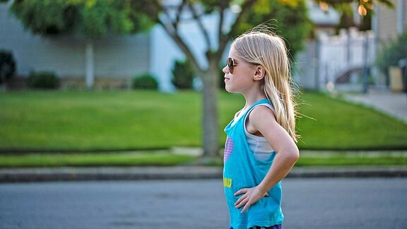 Ein kleines Mädchen mit Sonnenbrille und und in selbstbewusster Pose