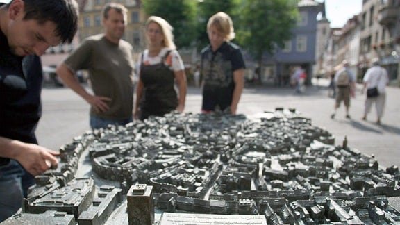 Touristen ertasten das Modell der Innenstadt für Blinde auf dem Fischmarkt in Erfurt.