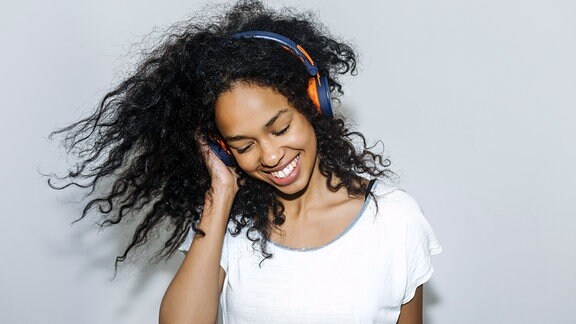 Eine junge Frau mit Kopfhörern erfreut sich am Musikhören.
