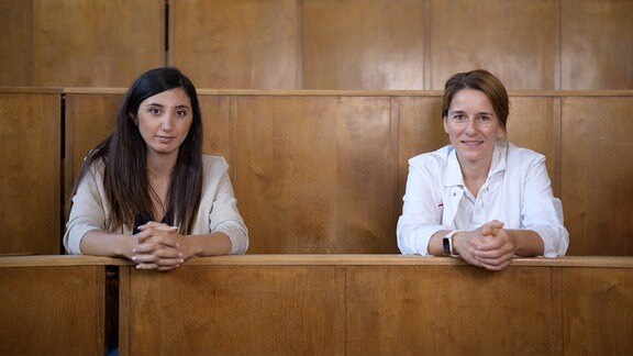 Zwie Frauen sitzen in einmUni-Hörsaal nebeneinander 