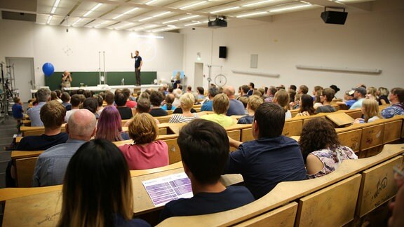 Besucher sitzen in einem Hörsaal.