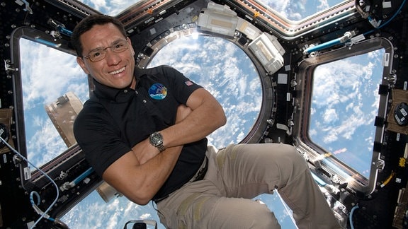 Der Nasa-Astronaut Frank Rubio auf der Internationalen Raumstation ISS. Er befindet sich schwebend in der Cupola, dem Aussichtsfenster zur Erde – die im Hintergrund zu erkennen ist.