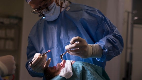 Ein Arzt entnimmt Knorpel aus der Nase eines Patienten.