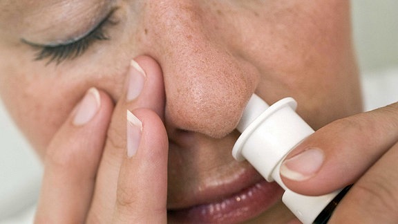 Eine Frau benutzt ein Nasenspray.