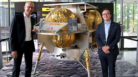 Arjan Sissing (DHL Markenchef, links) und Dan Hendrickson (Vice President of Business Development bei Astrobotic, rechts) vor einem Modell vom "Peregrine Luna Lander". Dieses Mondfahrzeug soll 2024 auf dem Mond landen. 