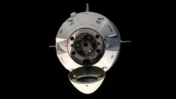 Ein Raumschiff im Weltall mit geöffneter Andockklappe.