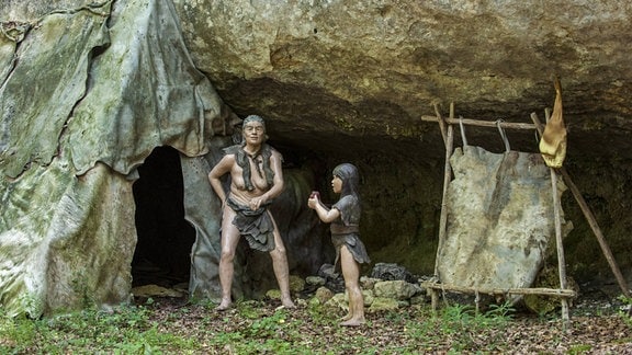 Diorama von halbnomadischen Neandertalern, die in einem Lager mit Unterschlupf aus Tierhäuten unter einem Felsüberhang im Prehisto Parc leben, Themenpark über prähistorisches Leben in Tursac, Périgord, Dordogne, Frankreich