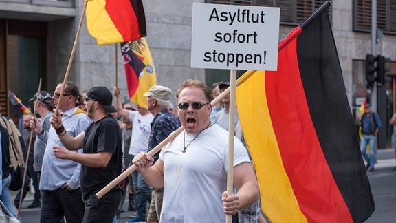 Berlin 2016 Demonstration Neonazis und Hooligans gegen Merkel Neonazis und Hooligans demonstrieren gegen Angela Merkel. Schreiender Mann mit Schild: " Asylflut stoppen!"