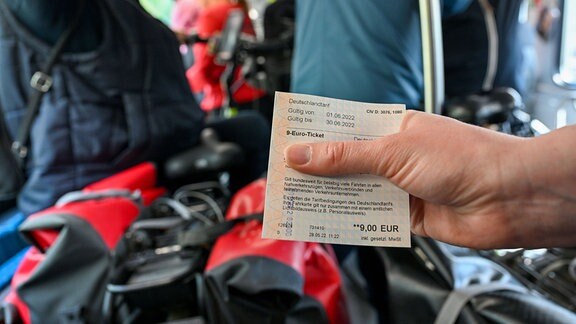 Eine Frau hält in einem Fahrradabteil ein 9-Euro-Ticket.