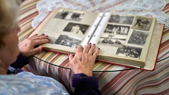 Eine ältere Frau blättert in einem Fotoalbum.