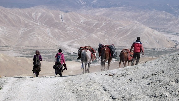 Händler und Reisende in der Region Oberer Mustang in Nepal mit Pferden über einen Gebirgspass