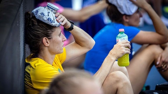 Eine Sportlerin hält sich einen Eisbjeutel zur Kühlung an den Kopf