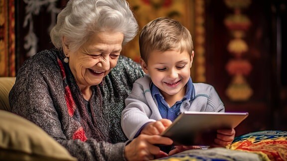 Eine Seniorin und ihr Enkel beugen sich über ein Tablet