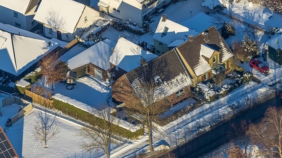 Vogelperspektive auf etwas verschneite Vorstadt-Wohnhäuser, Sonnenschein, Straßen, kahle Bäume