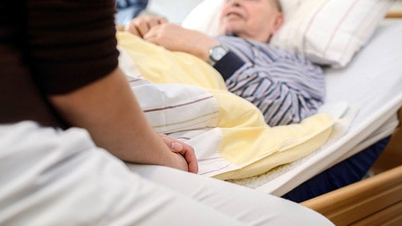 Pflegekraft am Bett eine Gastes in einem deutschen Hospiz, 2014