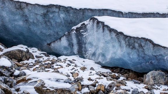 Eisschicht eines Gletschers auf hervorschauender Gesteinsschicht mit Schneeresten