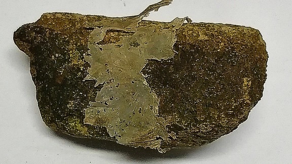 An diesem Stein, den chinesische Forschende aus erinem Bach geborgen haben, hat sich Mikroplastik angeheftet, das eine chemische Verbindung mit dem Stein eingegangen ist