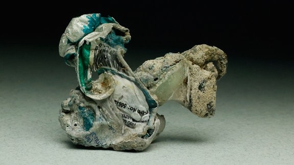 Ein beinahe Skulptur-ähnliches Stück verwitterter und geschmolzener Plastikmüll mit anhaftenden Sedimenten aus dem Meer.