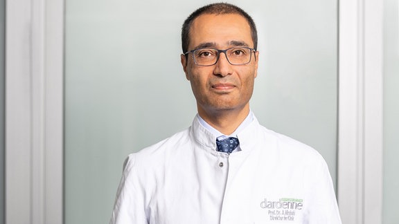 Das Bild zeigt einen Mann im weißen Arztkittel. Es ist der Augenarzt Alireza Mirshahi, Leiter der Augenklinik Dardenne in Bonn