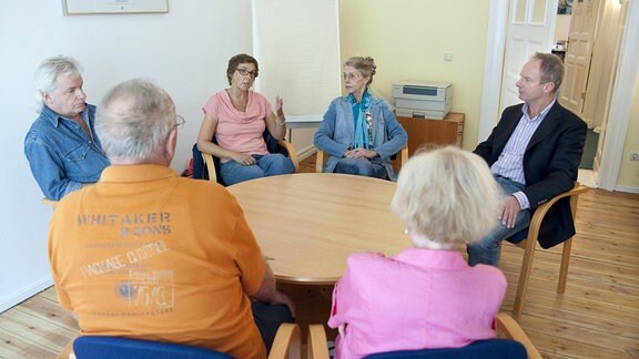Erwachsene sitzen an einem runden tisch. 