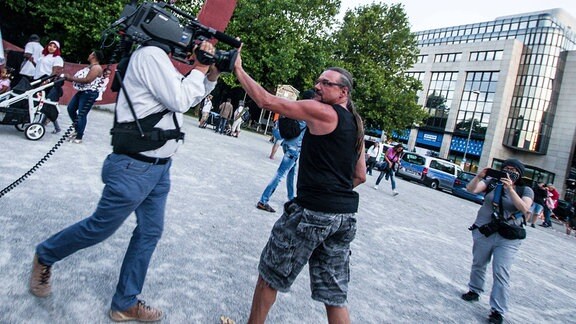Demonstrant attackiert Filmteam und hält Kamera zu