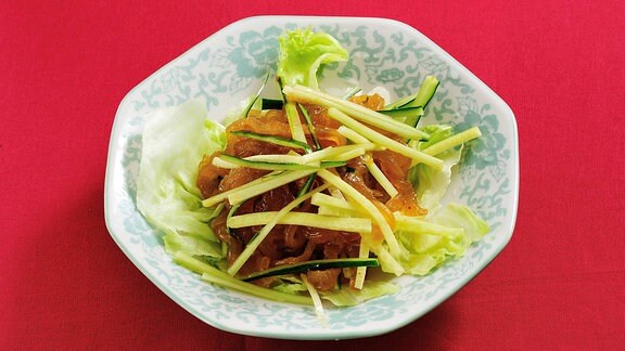 Asiatisches Quallengericht: Auf einem Teller sind Quallen in Soße mit Gemüse-Streifen angerichtet