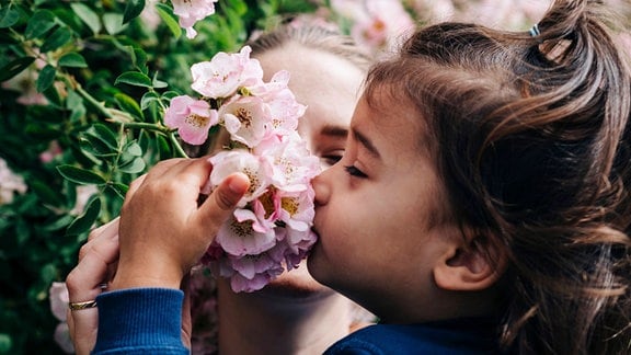 Mädchen riecht an einer Blume