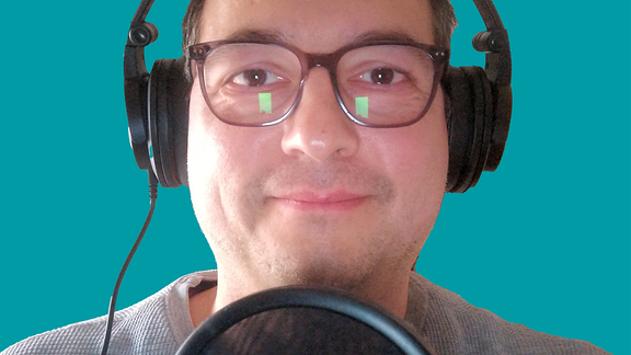 Mann mit Brille und Kopfhörern vor einem Mikrofon