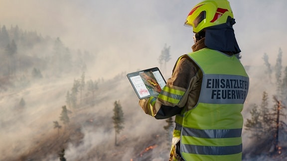 Ein Feuerwehrmann, der die App von OroraTech und Rosenbauer nutzt, um die Ausbreitung von Waldbränden zu erkennen.