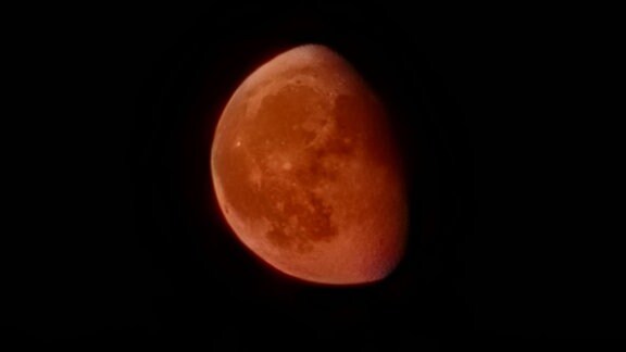 Mondes, dessen zur Erde reflektiertes Licht durch Staub in der Erdatmosphäre rot eingefärbt wird