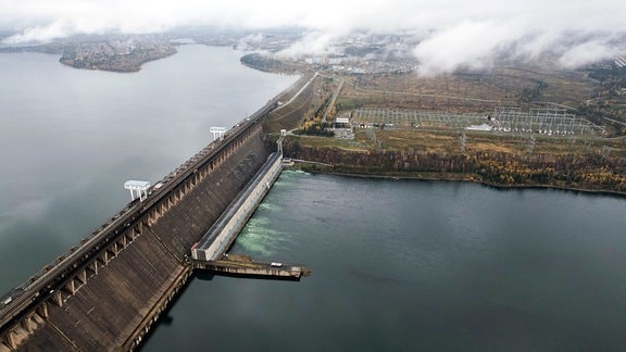 Luftaufnahme des Bratsk-Stausees und der Staumauer des Bratsk-Wasserkraftwerks am Fluss Angara im Herbst.