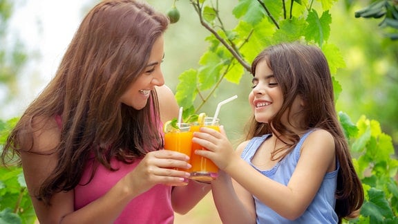 Mutter und Tochter fruen sich über ein Glas Fruchtsaft